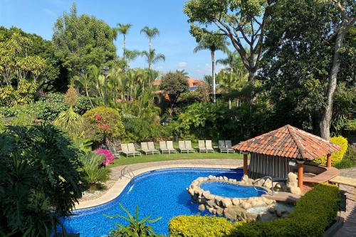 a swimming pool with a gazebo in a garden at Hosteria Las Quintas Hotel Restaurante Bar in Cuernavaca