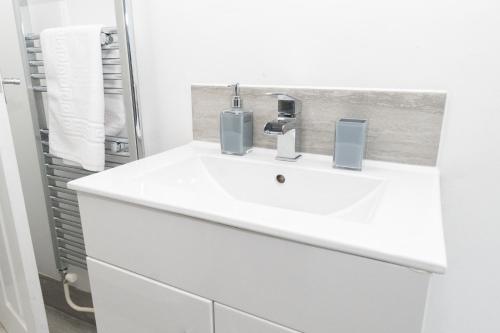 a white bathroom with a sink and a mirror at Business friendly 3BR home - King size beds & Centrally located in Swansea
