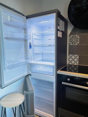 d'un réfrigérateur avec une porte ouverte et un tabouret. dans l'établissement Le Trois Fleurs, à Cherbourg en Cotentin