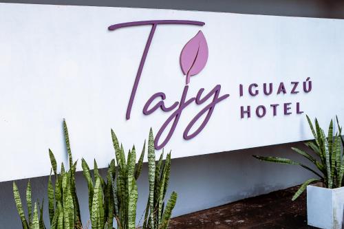 a sign for a hyundai la cruz hotel with plants at Tajy Iguazu Hotel in Puerto Iguazú