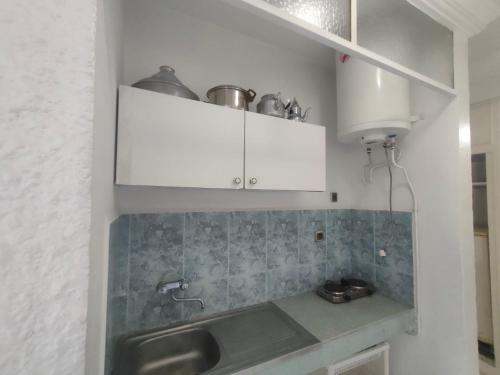 a kitchen with white cabinets and a sink at Hôtel Résidence Louban in Agadir