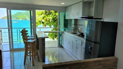 a kitchen with a refrigerator and a view of the ocean at Hospedaje El Shadday in Taganga