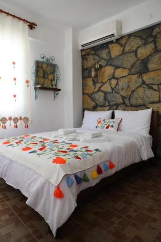 um quarto com uma grande cama branca e uma parede de pedra em Adahan Bozcaada Otel em Bozcaada