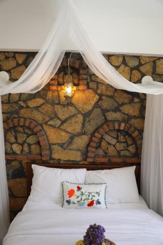 uma cama branca com uma parede de pedra atrás em Adahan Bozcaada Otel em Bozcaada