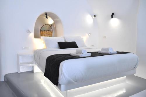 - une chambre blanche avec un grand lit blanc et des lumières dans l'établissement Oinos Luxury Suites, à Foinikiá
