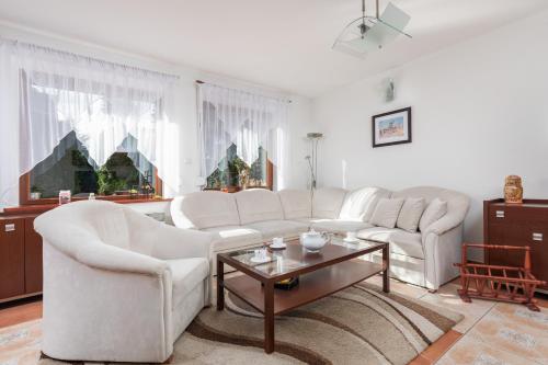 a living room with white couches and a coffee table at Holiday House "Słoneczna" with Garden by Renters in Łukęcin