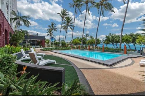 einen Pool in einem Resort mit Palmen in der Unterkunft Beachfront Balcony in North Ward