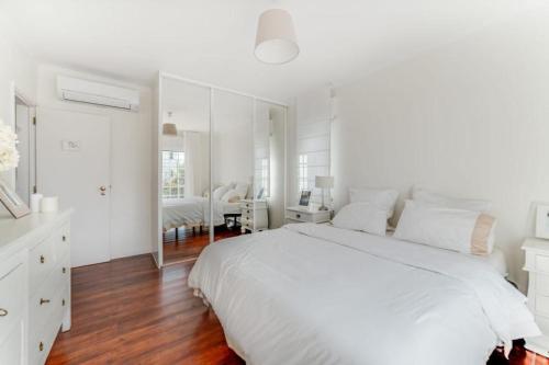1 dormitorio blanco con 1 cama grande y espejo en Casa da Praia, en Estoril
