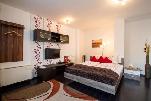 a bedroom with a bed with red pillows and a television at Budapest Center Executive Apartments in Budapest