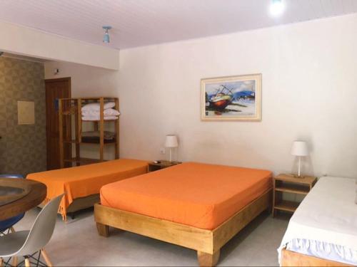 um quarto com 2 camas, uma mesa e uma cadeira em Suite Charme apt 02 em Ilhabela