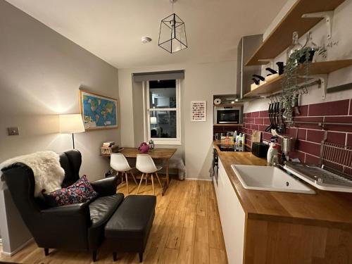 a kitchen and living room with a couch and a table at Small Cosy Studio Flat Near the Sea, Central Oban in Oban