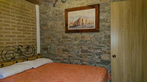 a bedroom with a bed and a painting on the wall at HOSTAL EL REFUGIO in Puebla