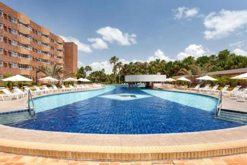 una gran piscina con sillas y sombrillas en Gran Lençóis Flat Residence Apartamento Atins 109 en Barreirinhas
