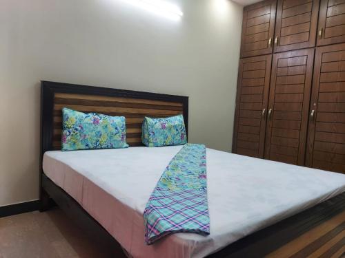 a bedroom with a bed with a white sheets and blue pillows at Defence Guest House in Karachi