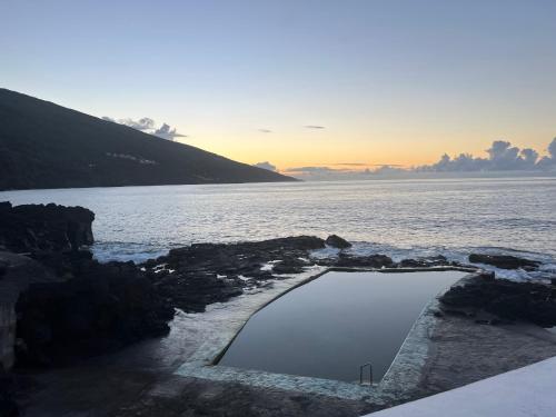a swimming pool on the shore of a body of water at Casa da Bicuda in Ribeiras