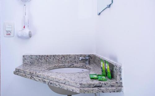 a bathroom sink with a granite counter top at Pousada Vila Barequeçaba in São Sebastião