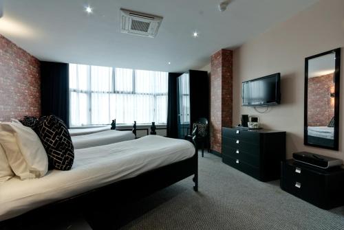 a bedroom with two beds and a flat screen tv at Print Works Hotel in Liverpool