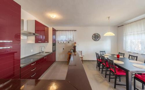 a kitchen with red cabinets and a table and chairs at Family-friendly apartments with swimming pool Stara Vas, Pag - 21031 in Pag