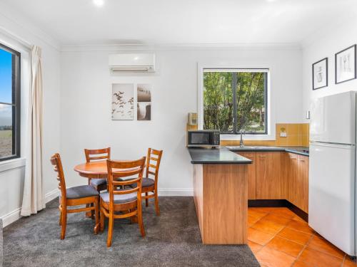 a kitchen with a table and chairs and a refrigerator at Leisure Inn Pokolbin Hill in Pokolbin