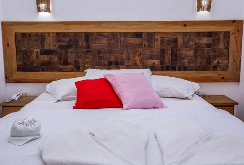 a white bed with two red pillows on it at Pousada Vila Barequeçaba in São Sebastião