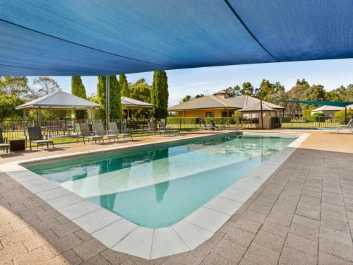 a large swimming pool with a blue canopy at Leisure Inn Pokolbin Hill in Pokolbin