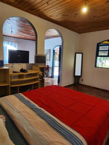 1 dormitorio con 1 cama grande de color rojo y escritorio en Hospedaria e Camping Quintal do Mundo, en Lumiar