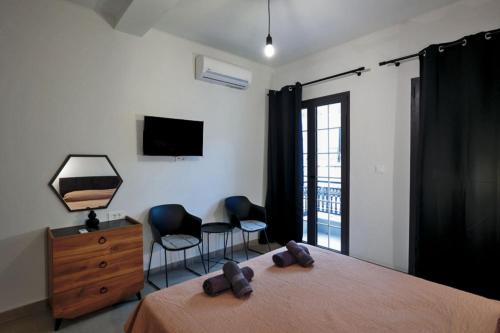 a bedroom with a bed and two chairs and a television at Sogni D' Oro "Zen" in Zakynthos Town