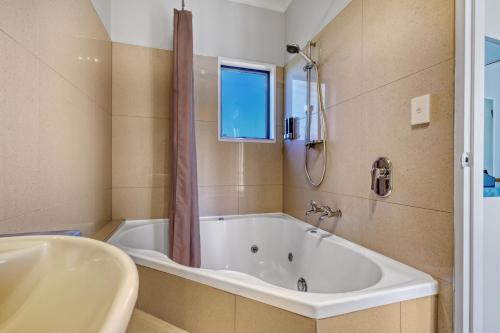 a bathroom with a tub and a sink and a window at Hanmer Springs Scenic Views Motel in Hanmer Springs