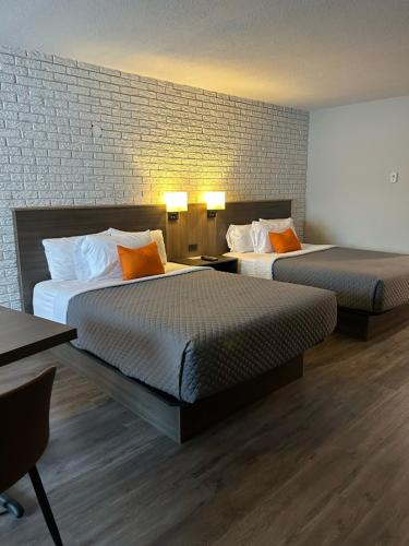 a hotel room with two beds and a brick wall at Complexe Dix80 in Mont-Laurier