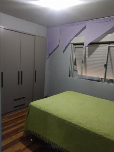 een slaapkamer met een groen bed en een raam bij Casa apto Bento Gonçalves Serra Gaúcha in Bento Gonçalves