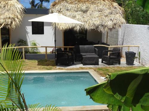 a swimming pool with chairs and an umbrella at BUNGALOWS COLIBRI in Las Galeras