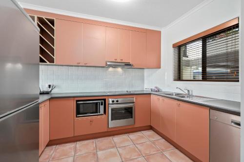 a kitchen with orange cabinets and a sink at Culgoa Point Beach Resort in Noosa Heads