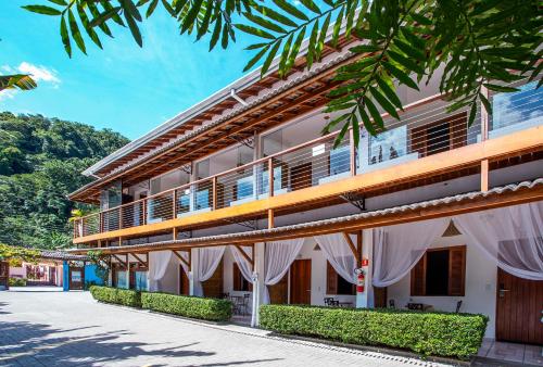a building with white curtains on the side of it at Pousada Vila Barequeçaba in São Sebastião