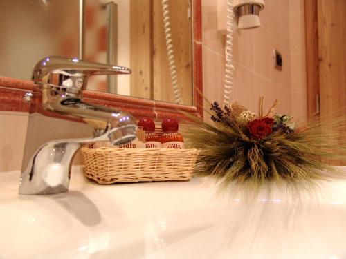 a bathroom sink with a faucet and a basket on it at Jolly B&B - Affittacamere in Dimaro