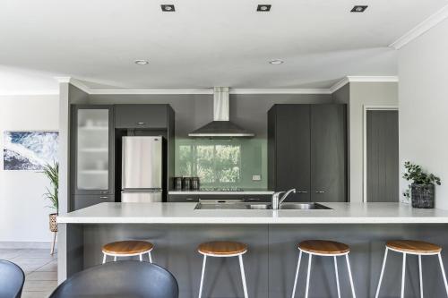 a kitchen with a white counter top and stools at Seagreen Bach in Raglan
