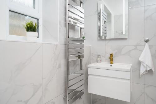 La salle de bains blanche est pourvue d'un lavabo et d'un miroir. dans l'établissement Boutique Flat near O2 & Excel, à Londres