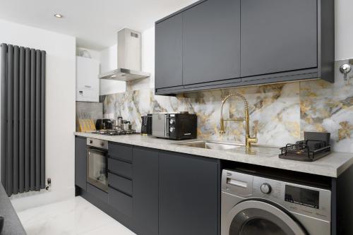 a kitchen with a sink and a washing machine at Boutique Flat near O2 & Excel in London