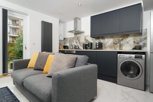 a living room with a couch and a washing machine at Boutique Flat near O2 & Excel in London
