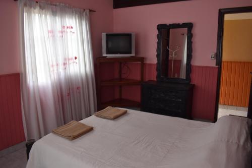 1 dormitorio con 1 cama con espejo y TV en Casa Lucía en Villa Unión