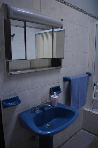 y baño con lavabo azul y espejo. en Casa Lucía en Villa Unión