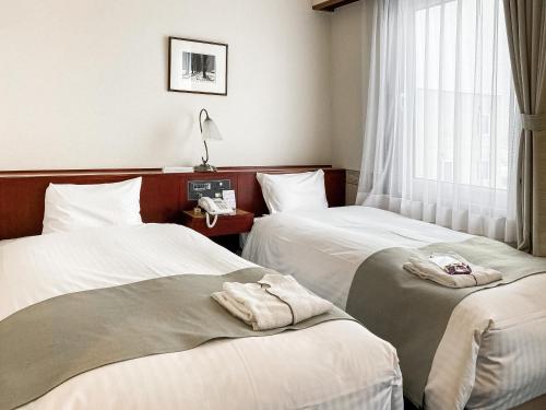 Dos camas en una habitación de hotel con toallas. en Tabist Abashiri Central Hotel, en Abashiri