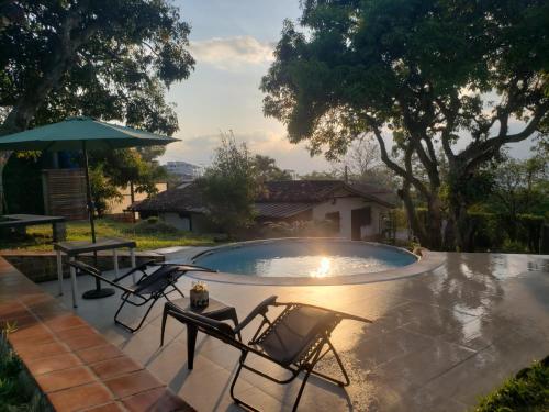 a pool with two chairs and an umbrella at La Cabaña Socorro in Socorro