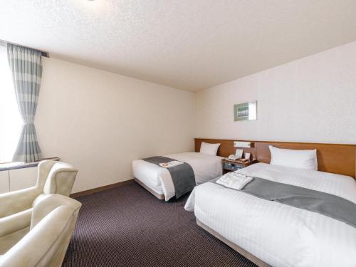 a hotel room with two beds and a couch at Tabist Abashiri Central Hotel in Abashiri