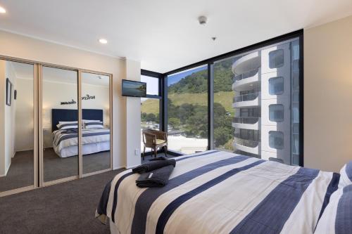 a bedroom with a large bed and large windows at Oceanside Marine Pde Magic in Mount Maunganui