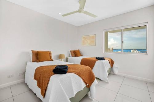 a white room with two beds and a window at Spectacular Darwin apartment in Darwin