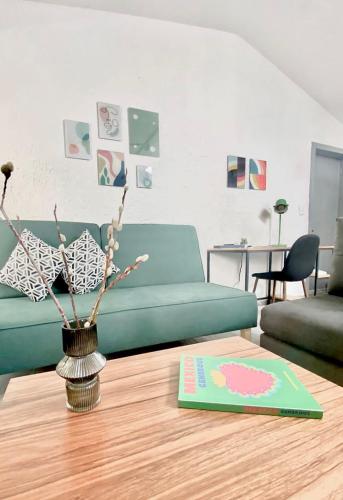 a living room with a green couch and a vase on a table at Departamento tipo LOFT cerca de hospital Angeles in Mexico City