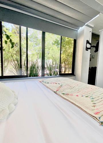 ein weißes Bett in einem Zimmer mit einem großen Fenster in der Unterkunft Departamento tipo LOFT cerca de hospital Angeles in Mexiko-Stadt