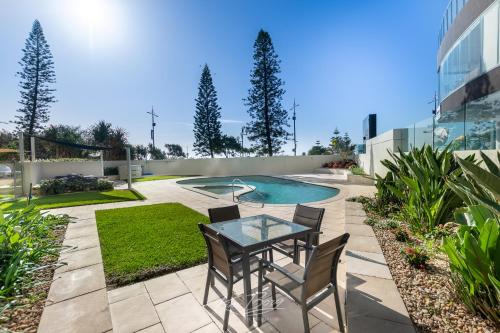 a patio with a table and chairs next to a pool at Zenith Ocean Front Apartments in Gold Coast