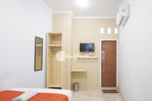 a bedroom with a bed and a tv on a wall at Tassa Homestay Syariah Mitra RedDoorz in Jambi