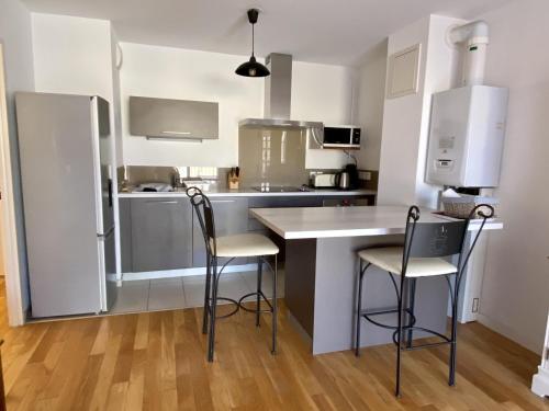 une cuisine avec un comptoir et trois chaises dans l'établissement Appartement central à Arcachon pour 2 personnes avec terrasse et parking - FR-1-474-38, à Arcachon